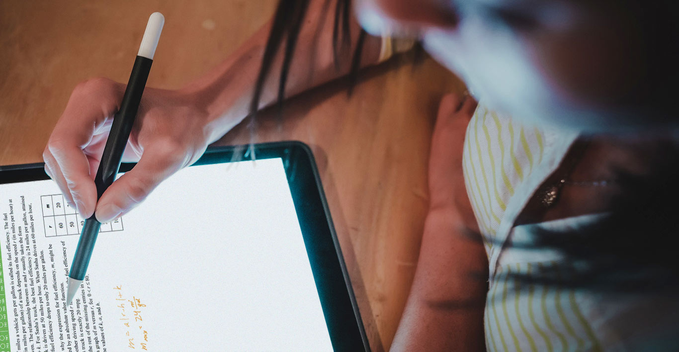 a student writes on a tablet while working on an AEON School math notebook