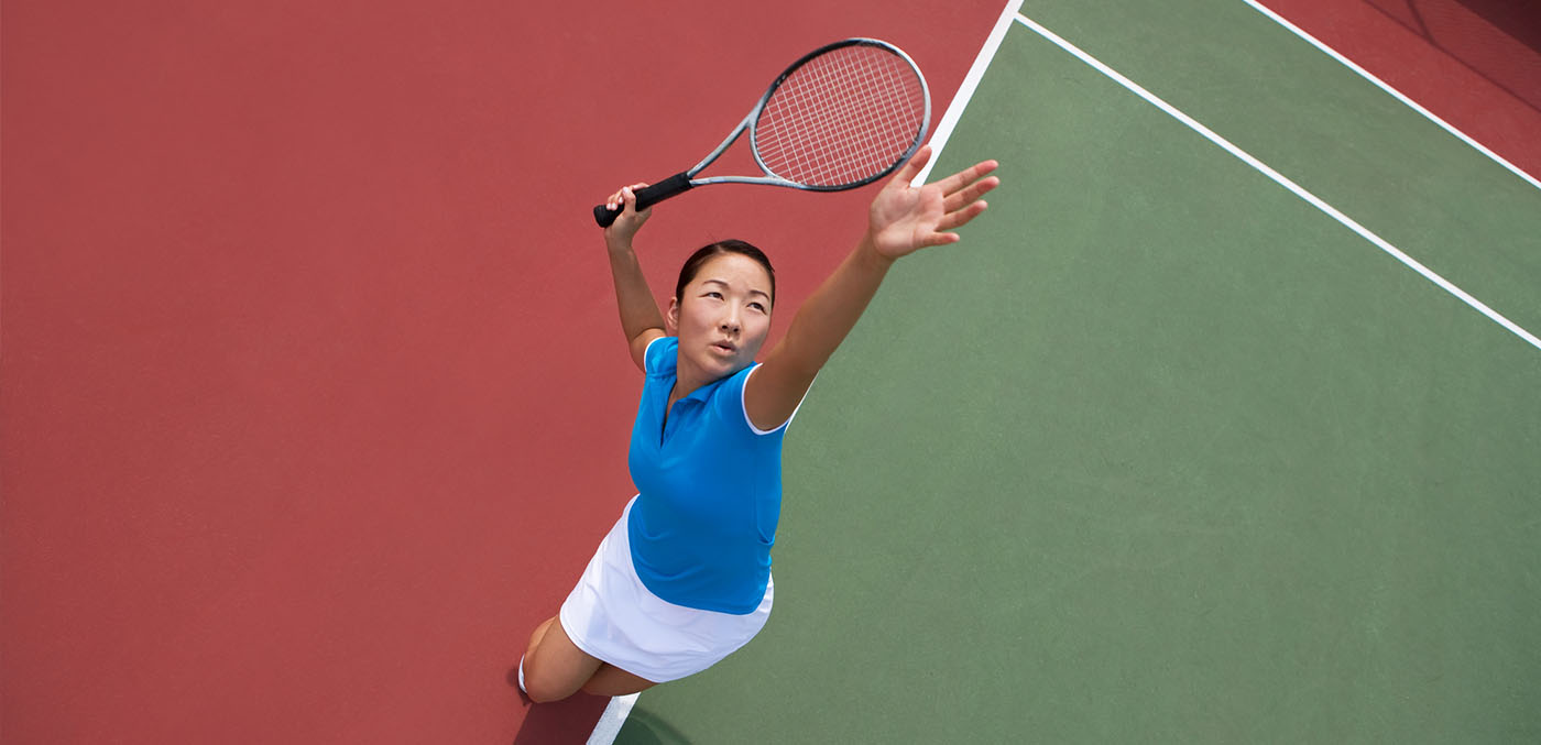 an Asian female tennis player serving, as seen from overhead