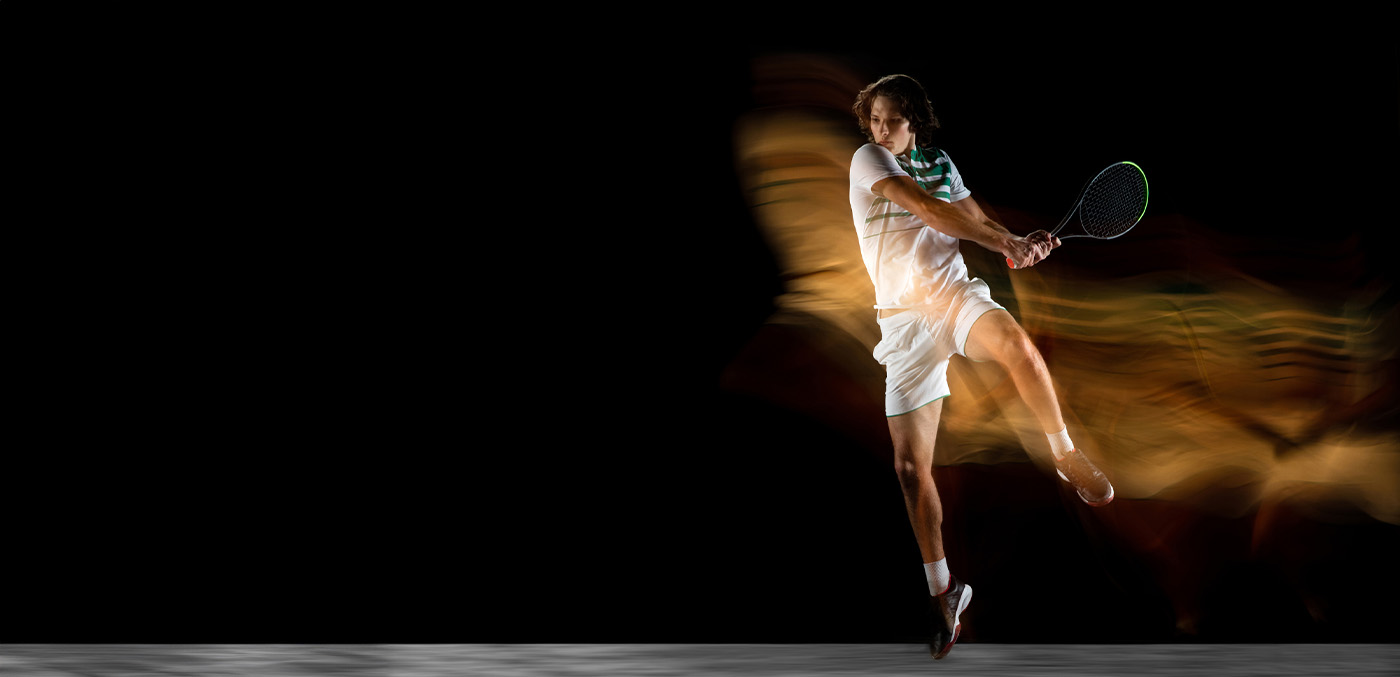 a young male tennis player’s backhand is seen as a motion blur