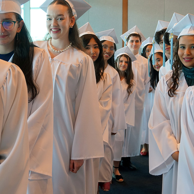 students wearing caps and gowns line up for the AEON School graduation